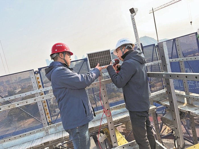 鲍大鑫（右）和同事在给轻量化造楼机安装传感器，通过数据监测管控实现智能建造。本报记者 赖志凯 摄
